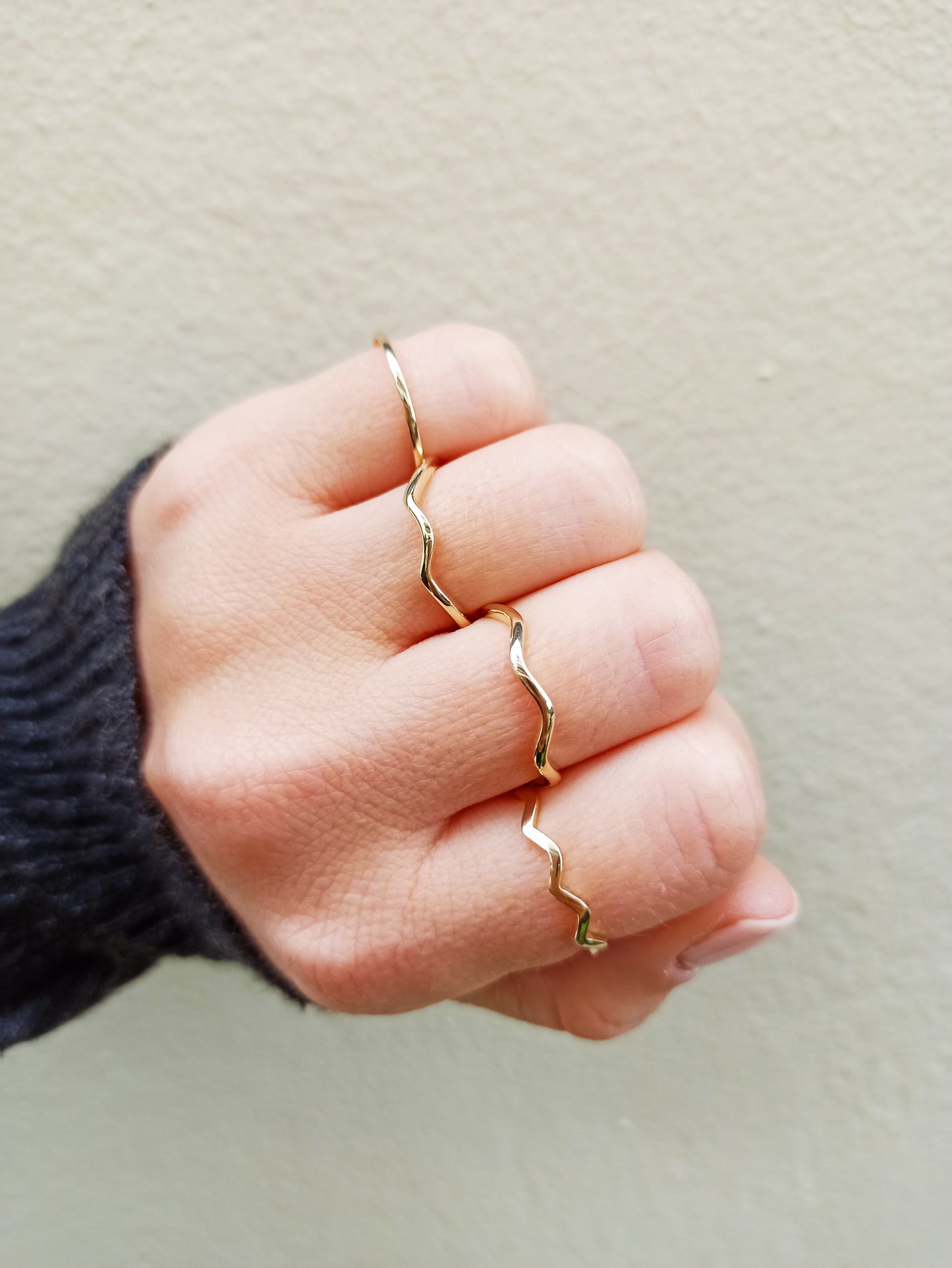 This image features a hand adorned with delicate gold rings, twisted bands, and minimalist designs.