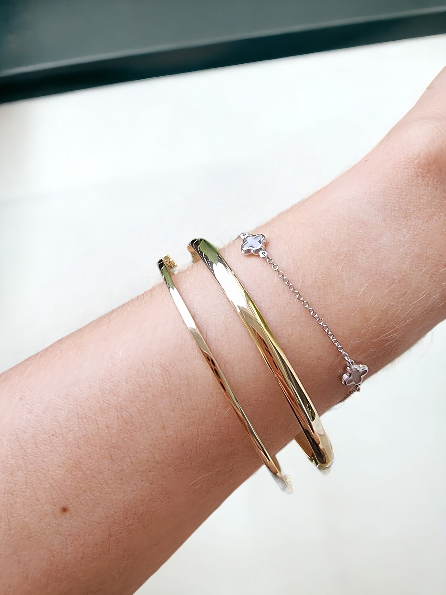 Different styles of bracelets: two bangle bracelets and one clover bracelet.