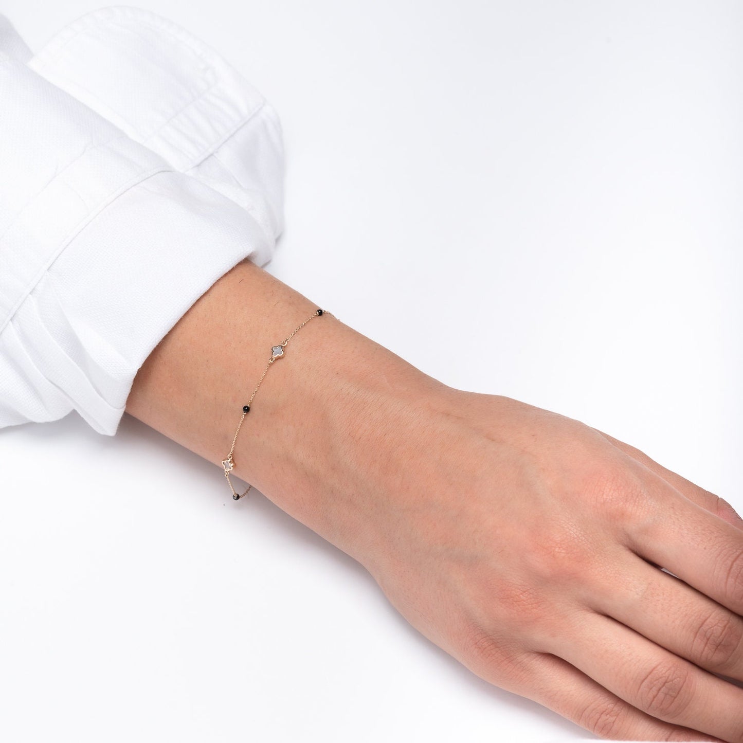 14k gold bracelet with four colver charms and three black onyx beads worn by a model
