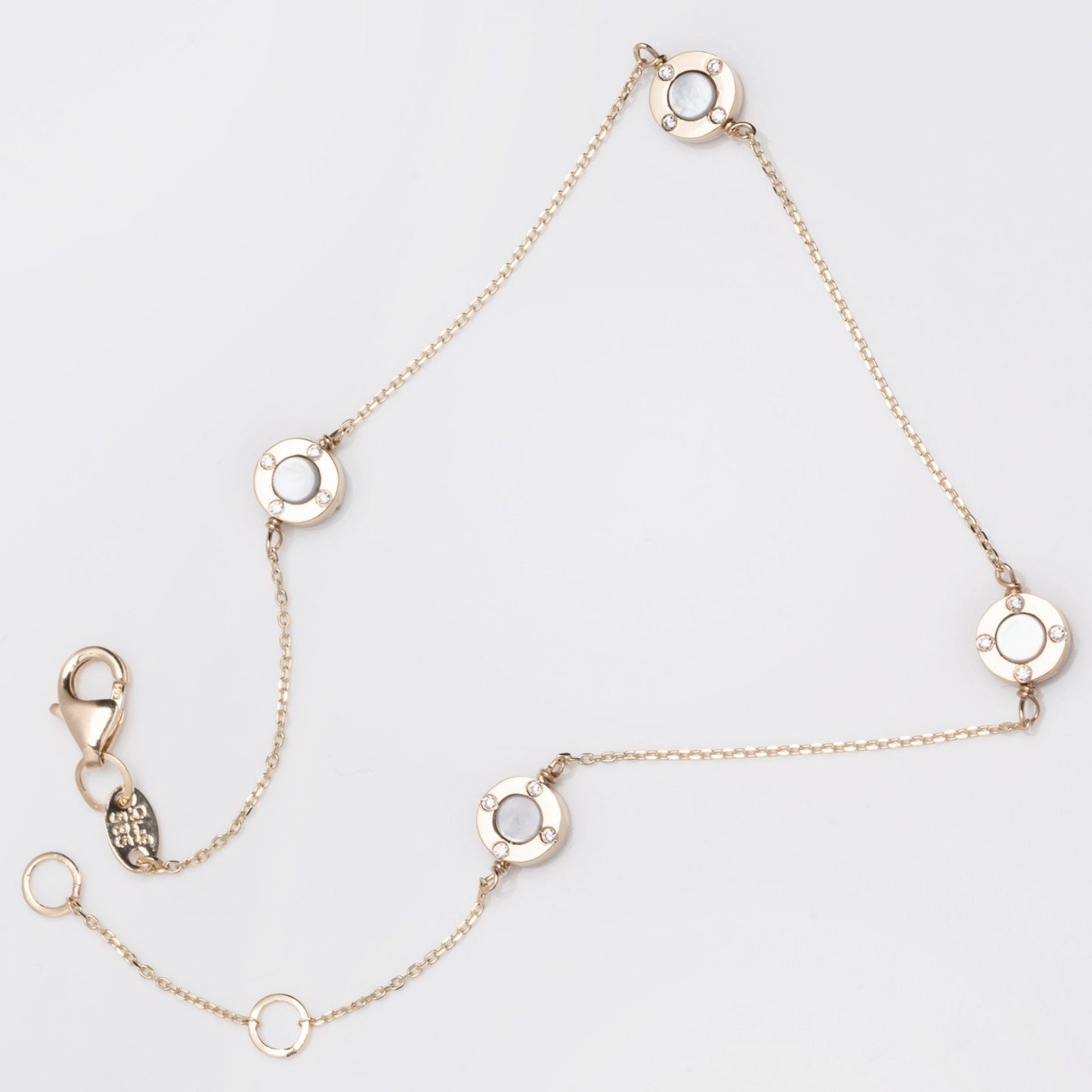 A model wears a Mother of Pearl bracelet featuring four circles and cubic zirconia stones set in 14k gold.