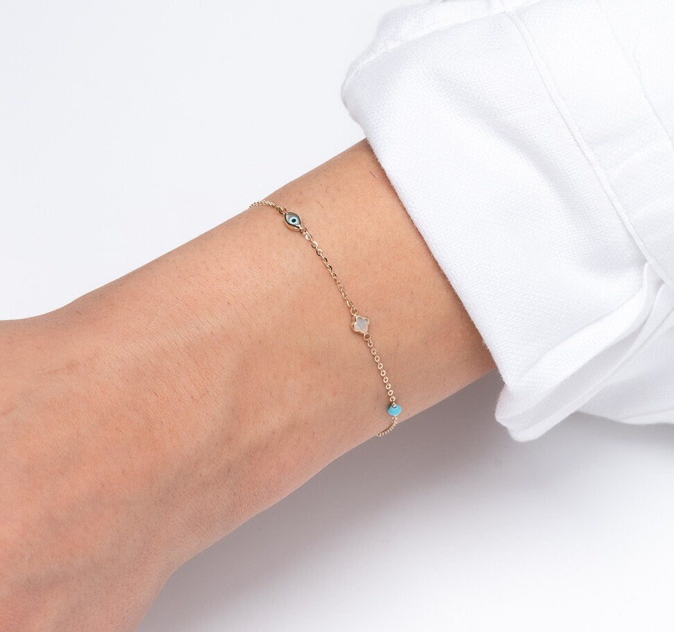 14k gold charm bracelet with afour leaf clover,heart,evil eye, turquoise and tourmaline stone worn by a model