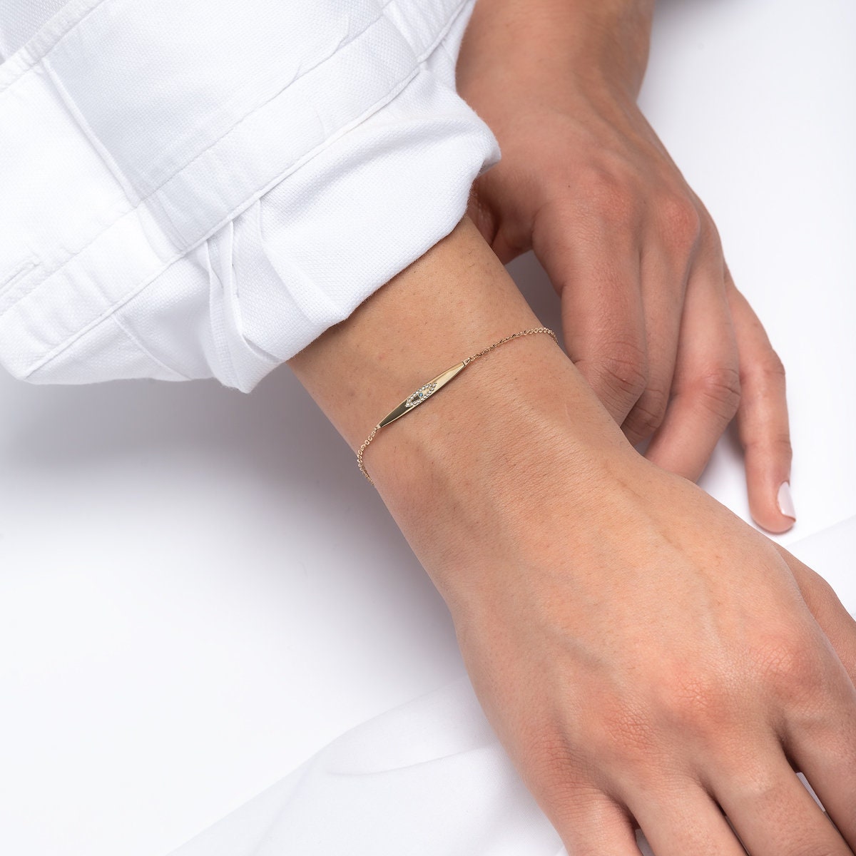 evil eye ID bracelet in 14k yellow gold worn by a model