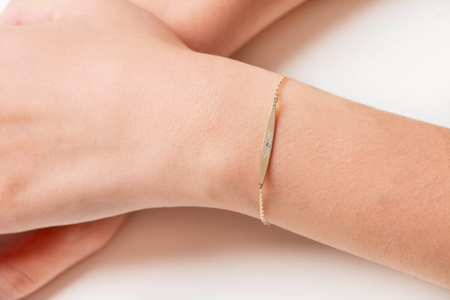 evil eye ID bracelet in 14k yellow gold worn by a model