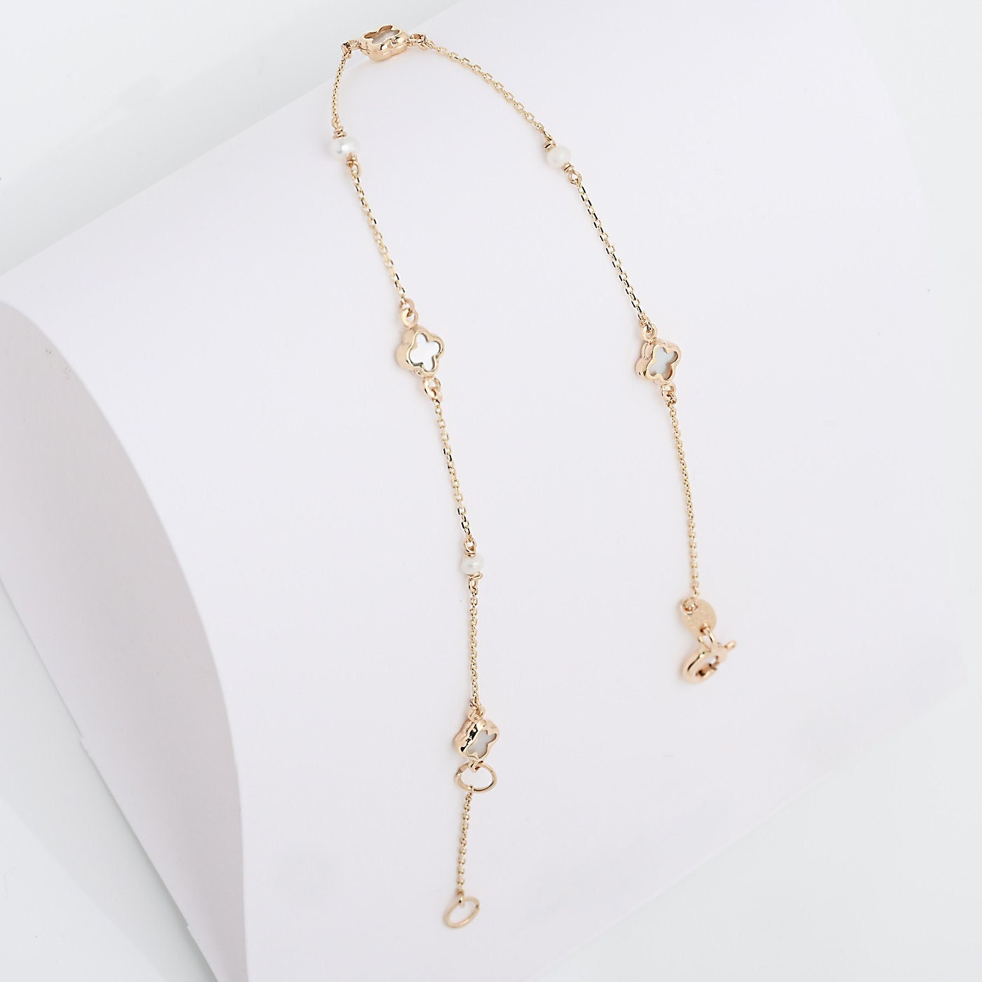 station bracelet adorned with pearl accents, and clover-shaped motifs made of mother of pearl
