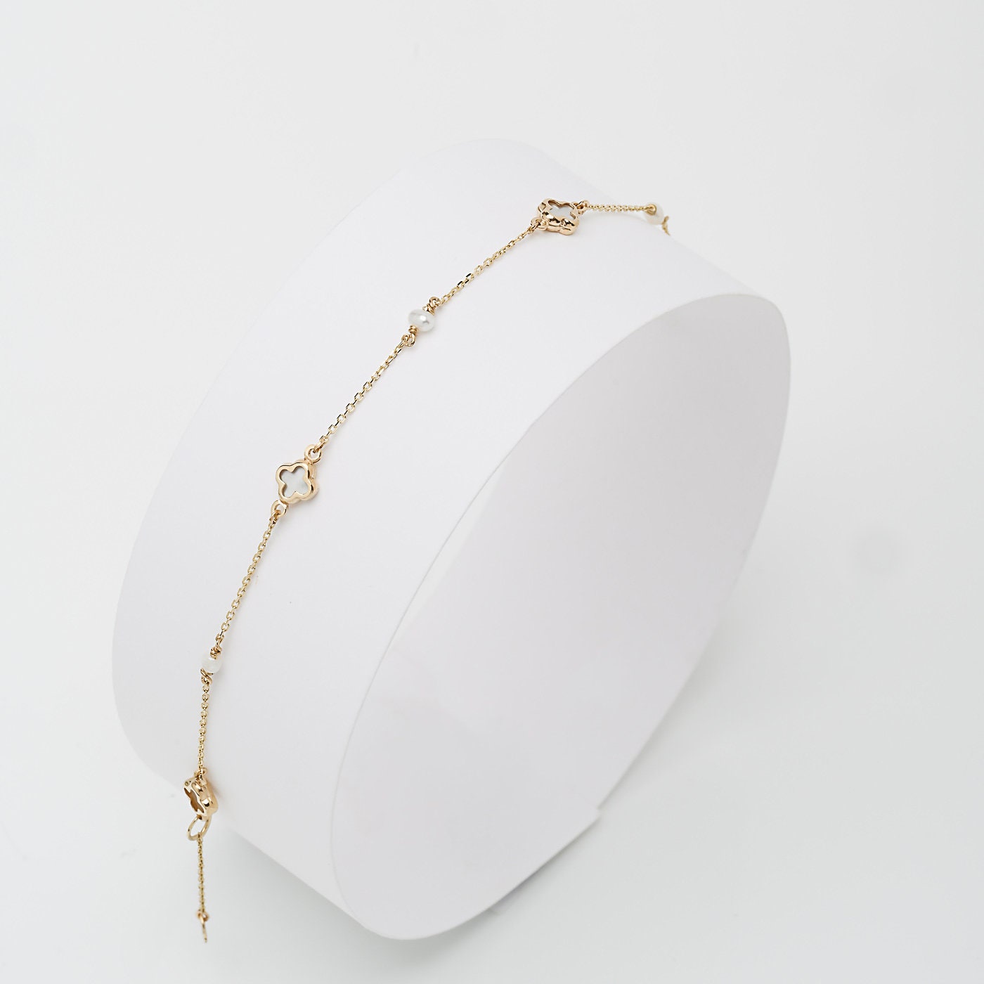 station bracelet adorned with pearl accents, and clover-shaped motifs made of mother of pearl