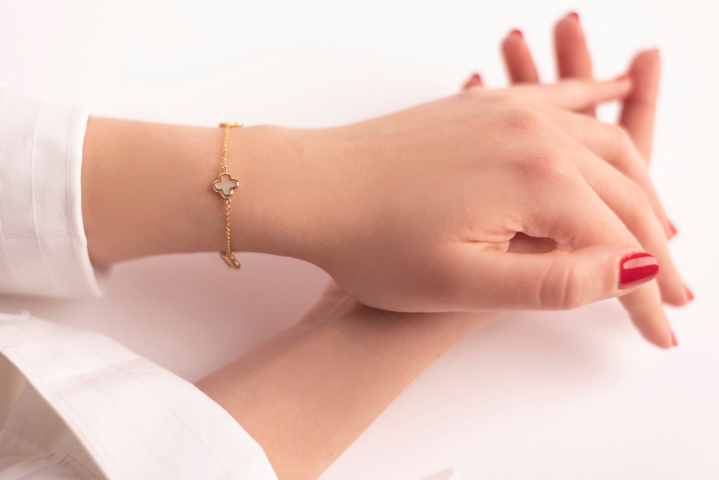 four leaf clover bracelet with 3 charms in 14k gold worn by a model