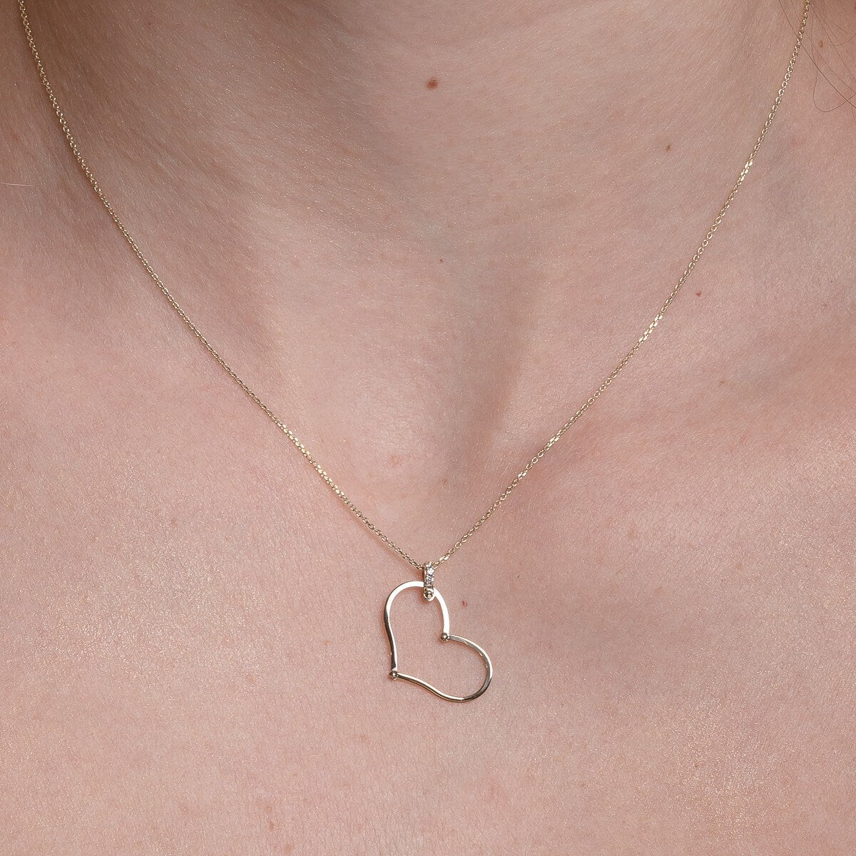 Large Heart Necklace in 14k solid gold with cubic zirconia stones on the loop worn by a model