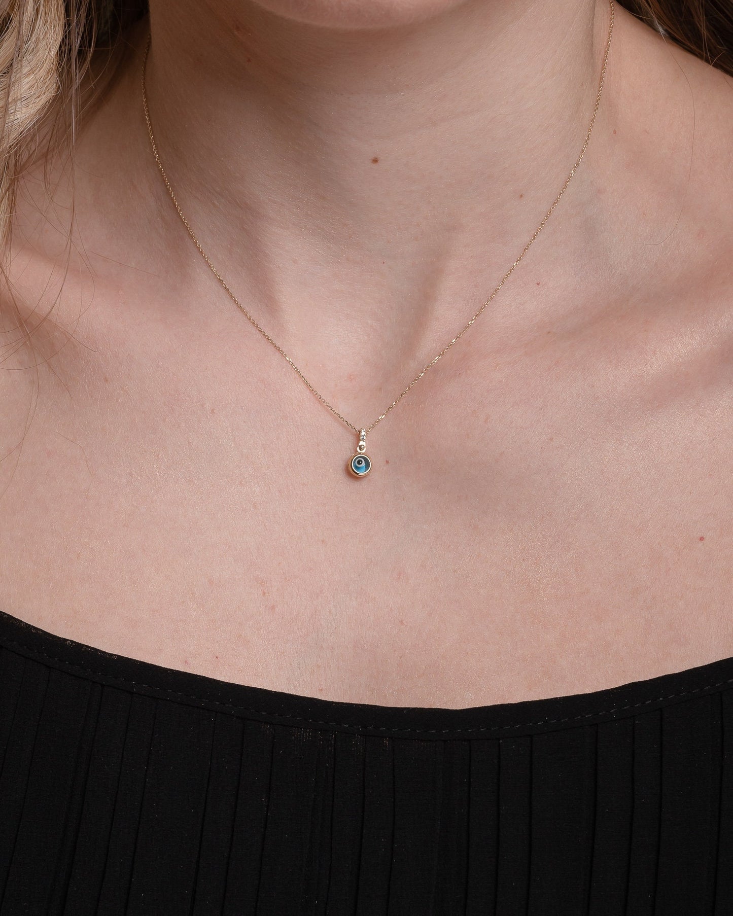 Murano glass evil eye necklace in 14k gold with cubic zirconia stones on the loop for women worn by a model