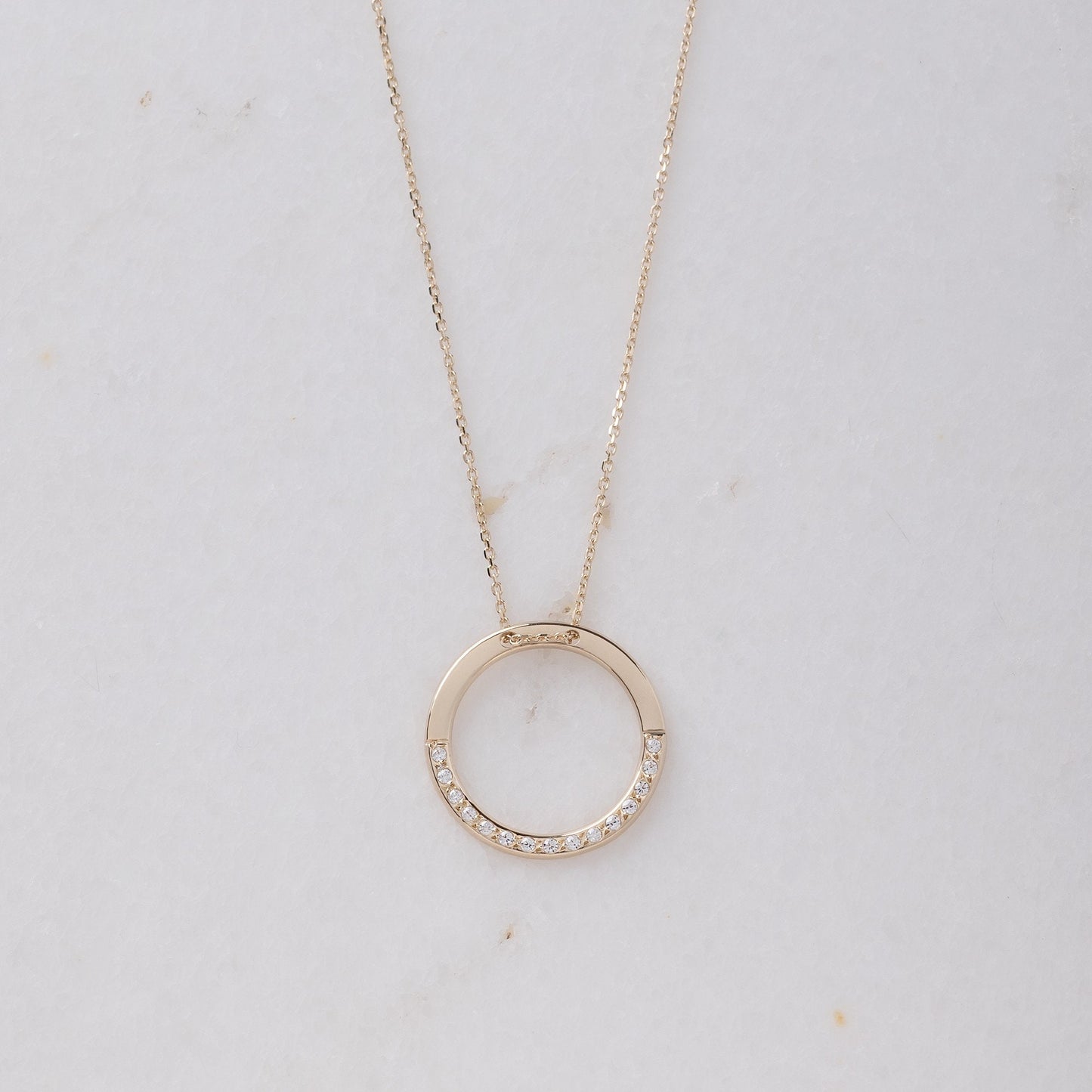 circle karma necklce in 14k gold half of the necklace is paved with cubic zirconia stones