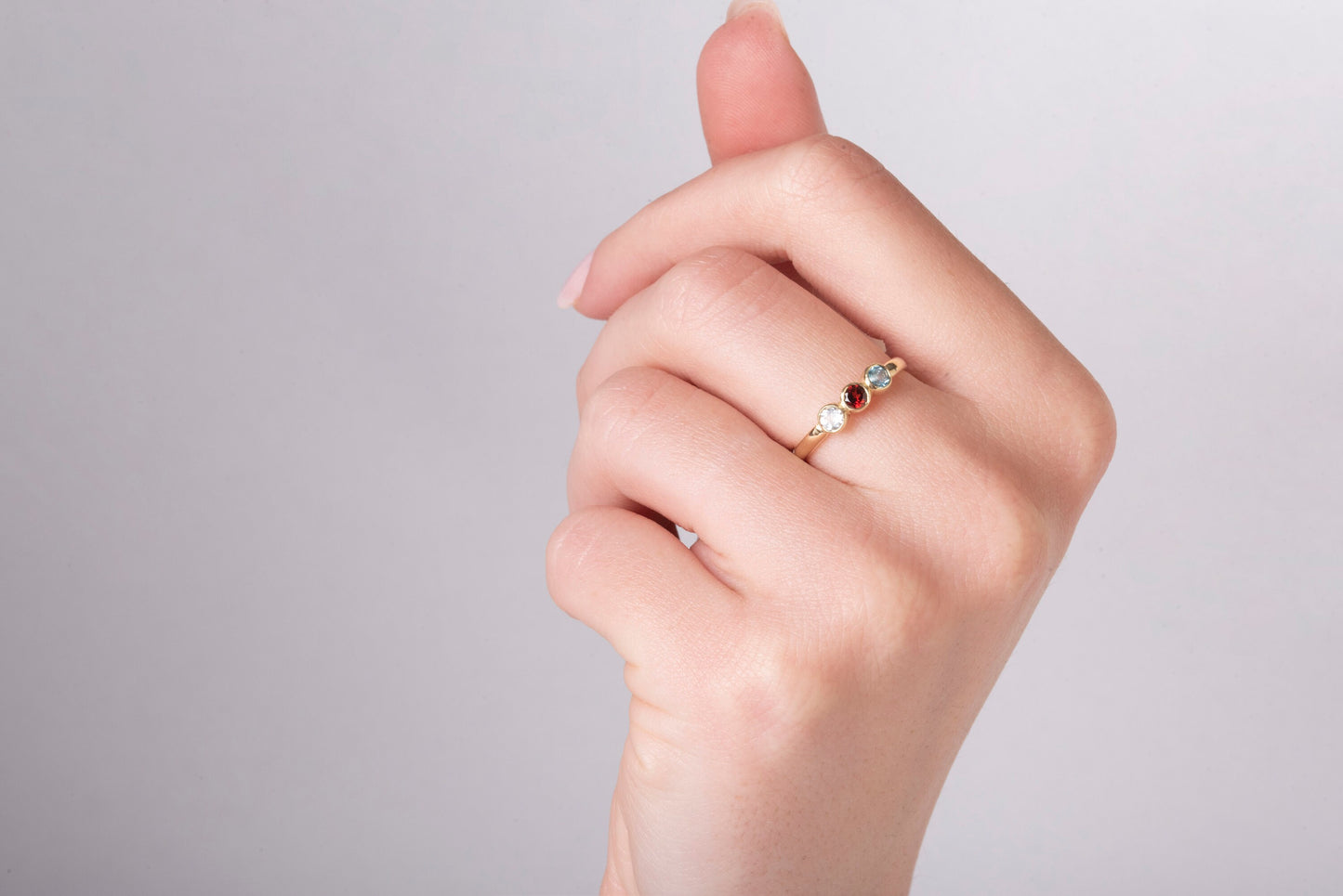 A handmade ring featuring three birthstones set in a bezel, crafted in 14k solid gold.