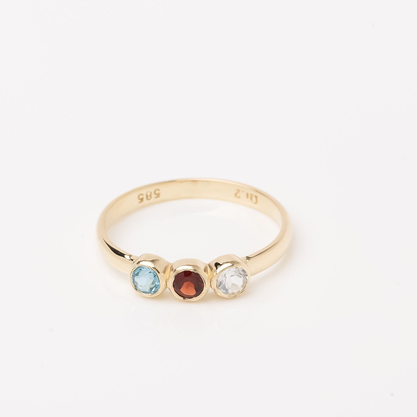 A handmade ring featuring three birthstones set in a bezel, crafted in 14k solid gold.