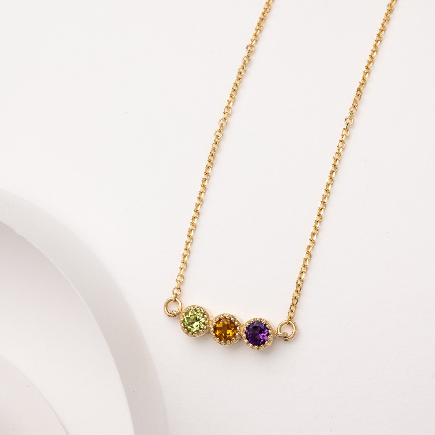 Handcrafted birthstone necklace in 14k gold, featuring three stones in a prong setting.