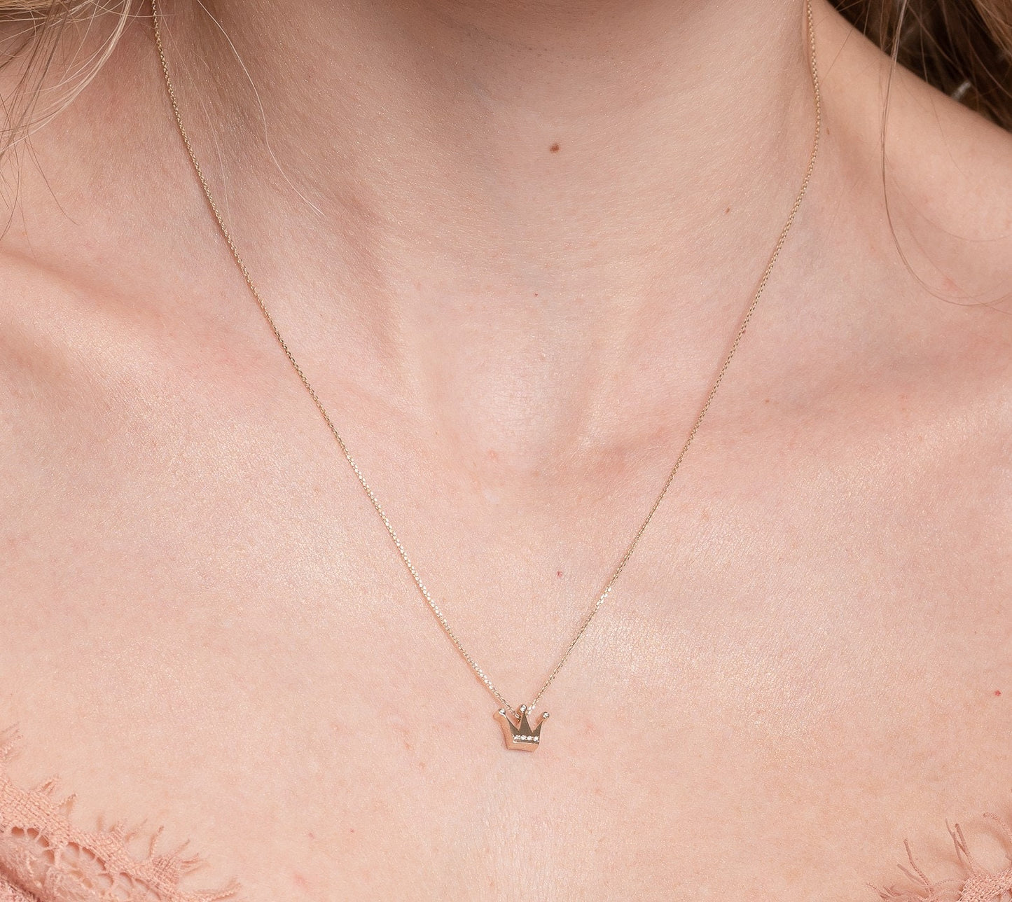 crown necklace in 14k yellow gold with cubic zirconia stones worn by a model