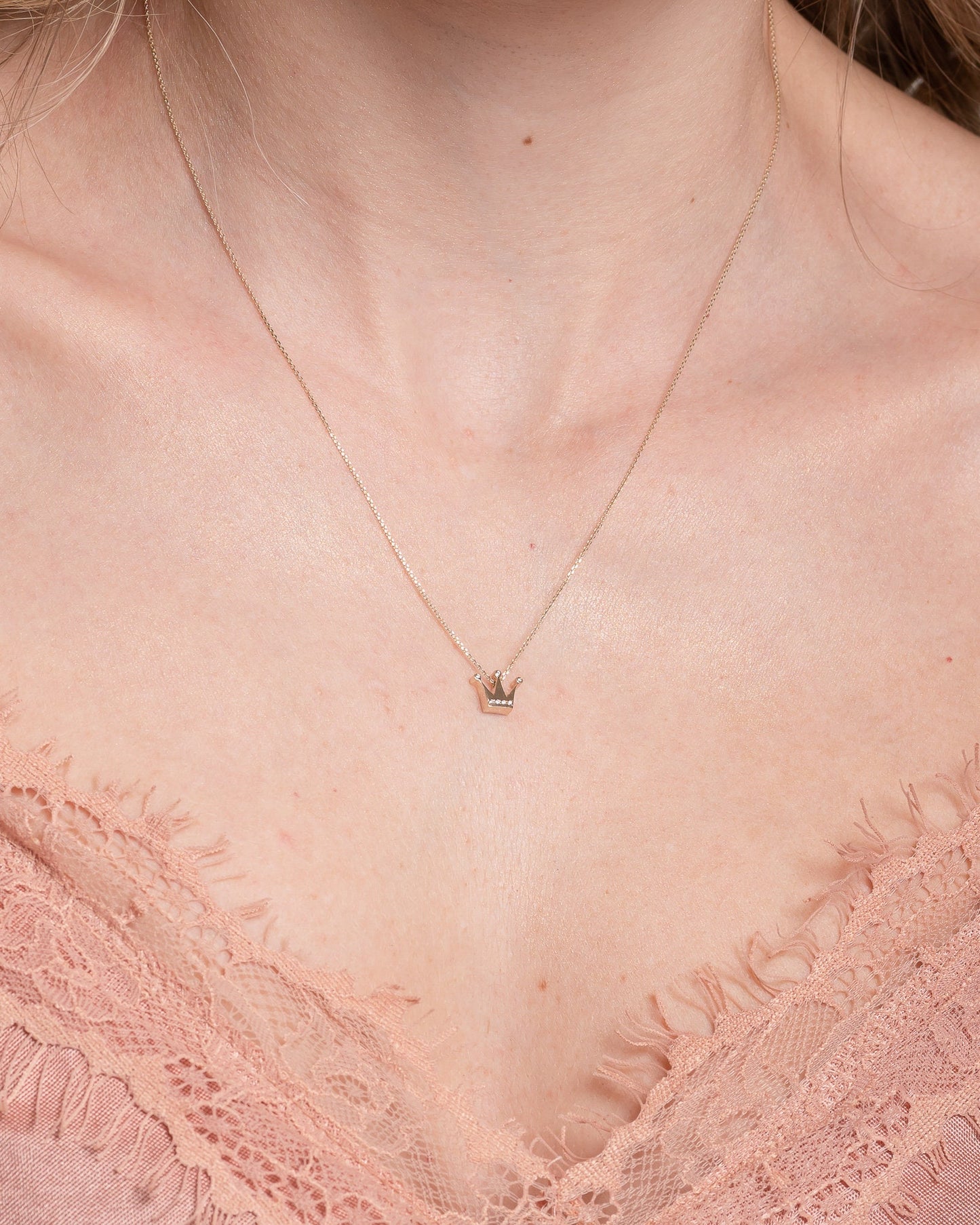 crown necklace in 14k yellow gold with cubic zirconia stones worn by a model