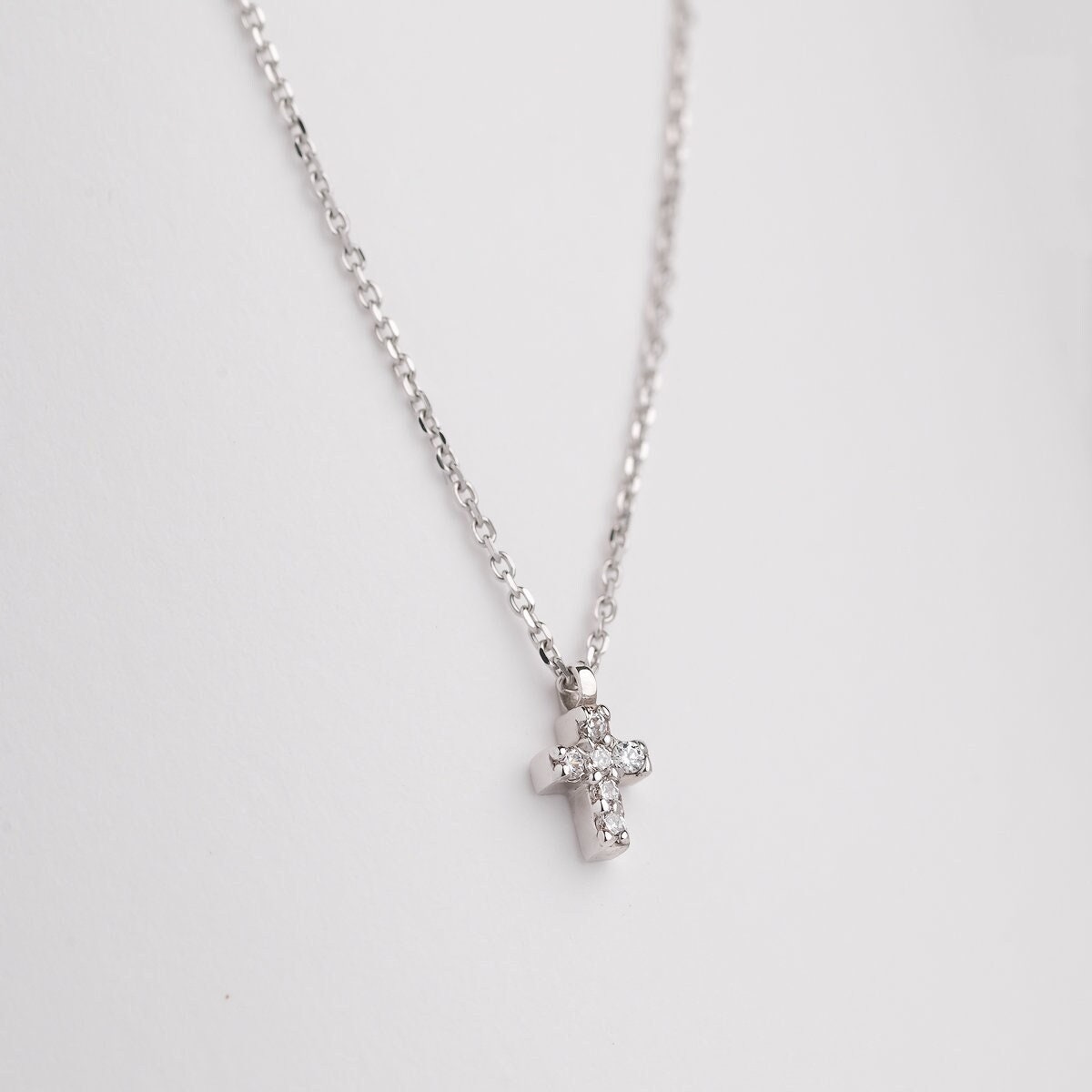 tiny diamond cross necklace in 14k white gold for women wron by a model