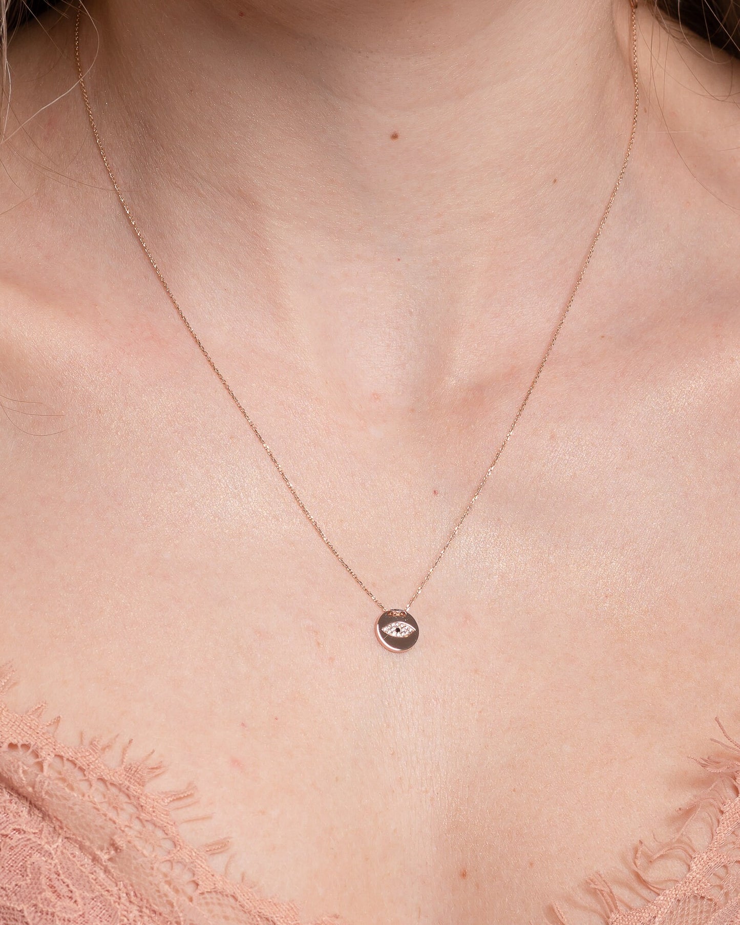 Pavé evil eye necklace in 14k yellow gold for women worn by a model