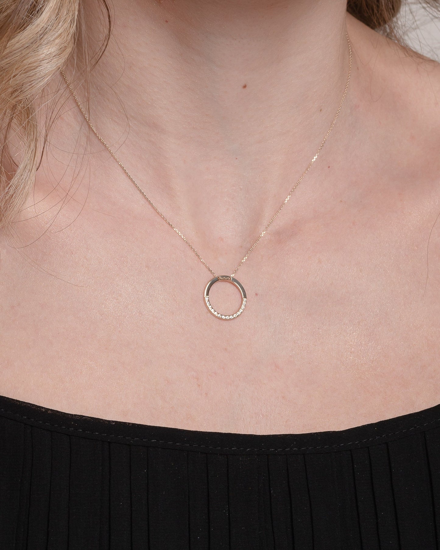 circle karma necklce in 14k gold half of the necklace is paved with cubic zirconia stones worn by a model