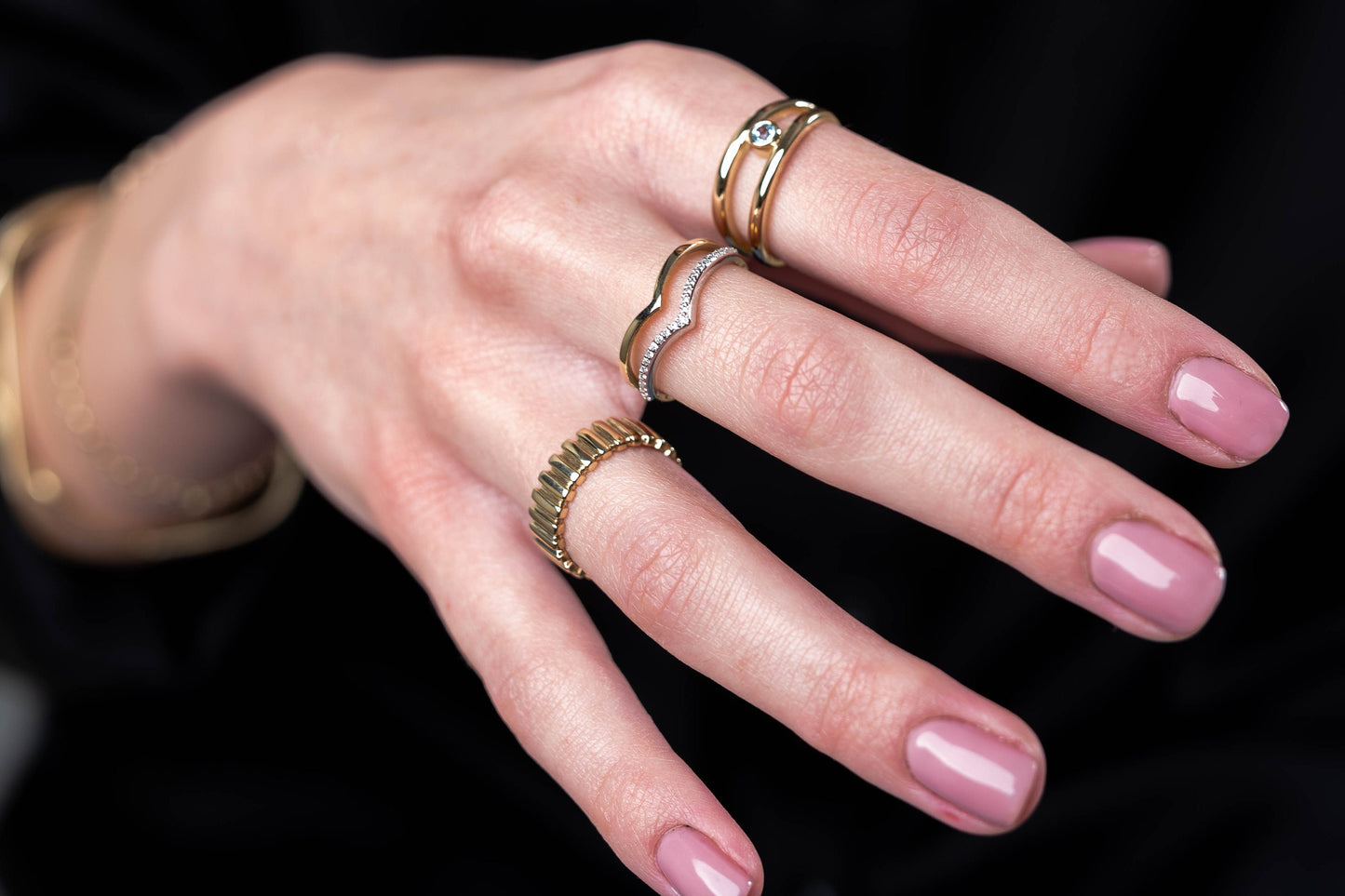 This image features a hand adorned with delicate gold rings, showcasing a variety of styles including gemstone accents.