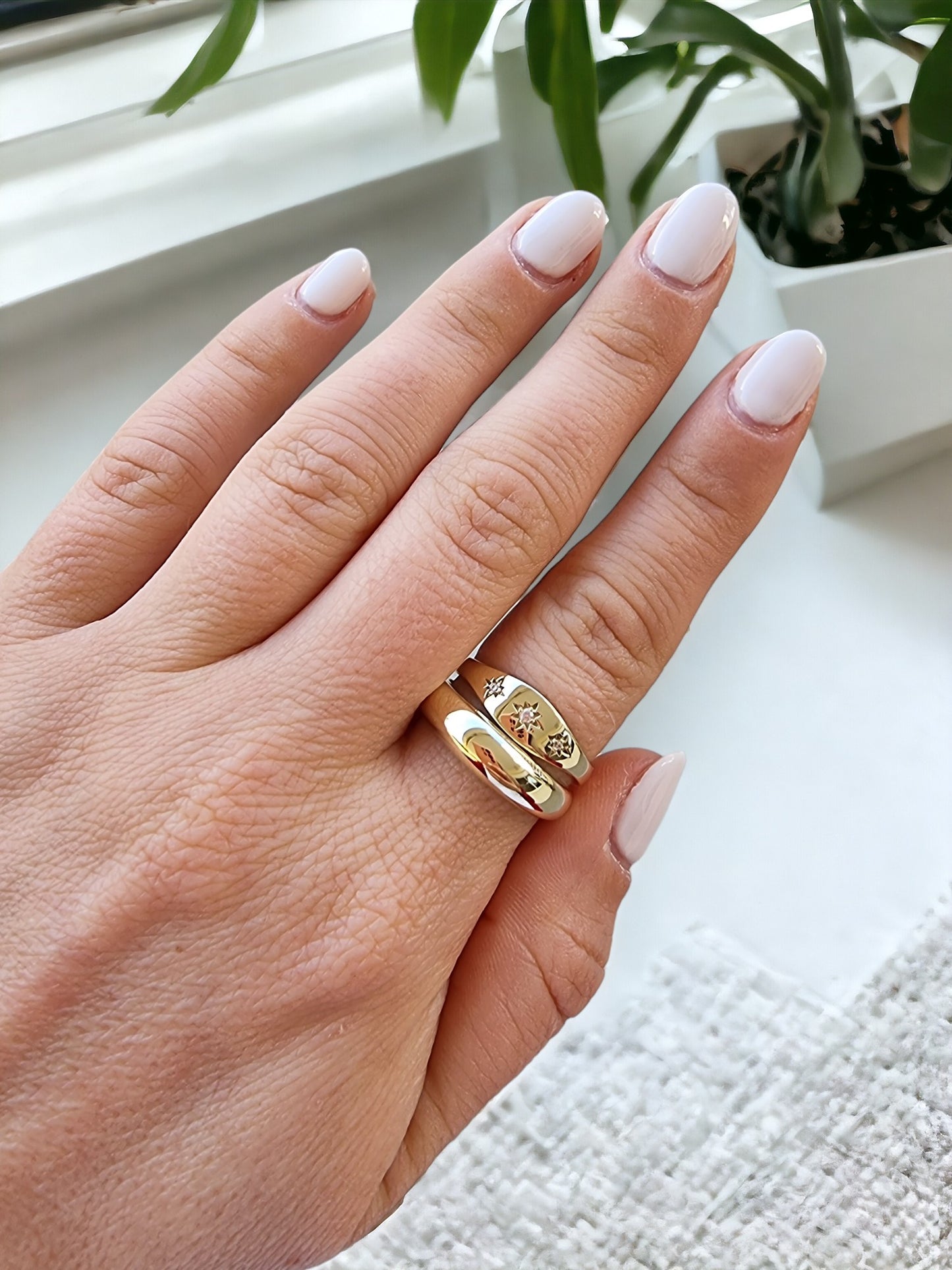 A model wears a handmade dome and starburst ring crafted in 14k solid gold on her index finger.