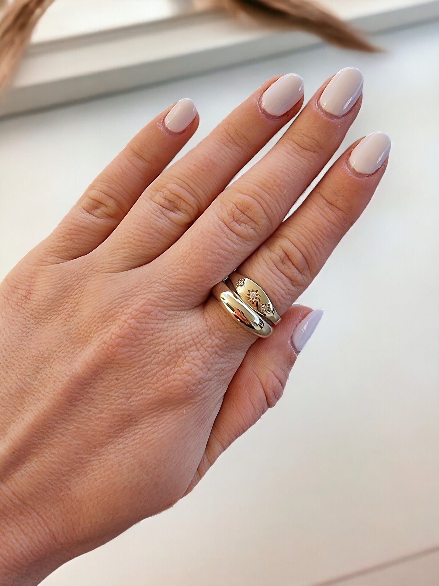 A model wears a handmade dome and starburst ring crafted in 14k solid gold on her index finger.