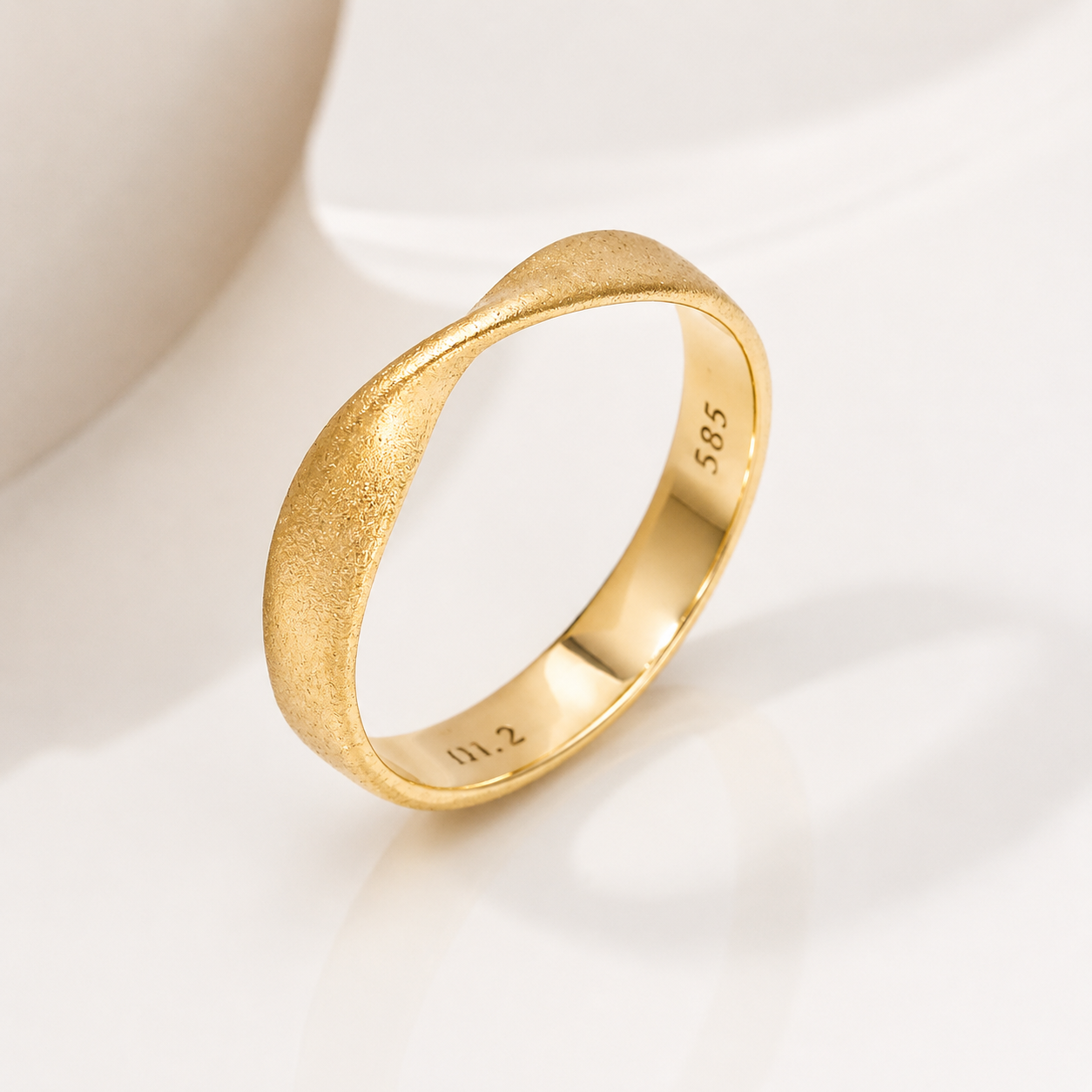 14k Gold mobius ring with a textured band on a white background