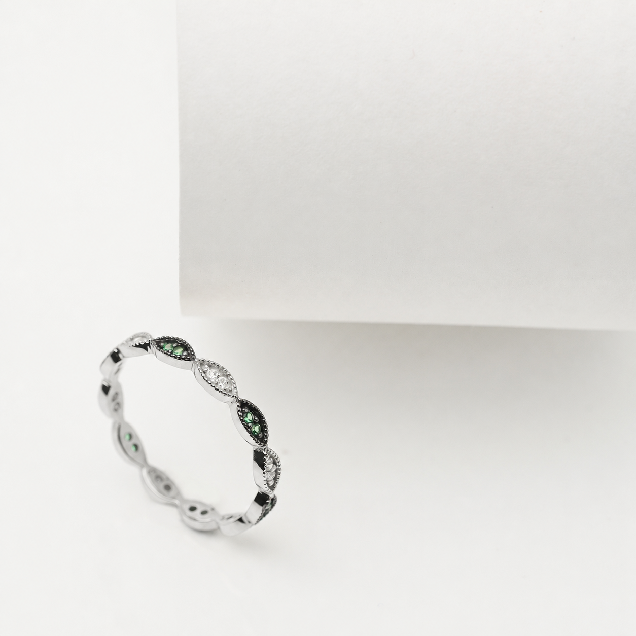 14k white Gold ring with green and white cubic zirconia stones on a white background