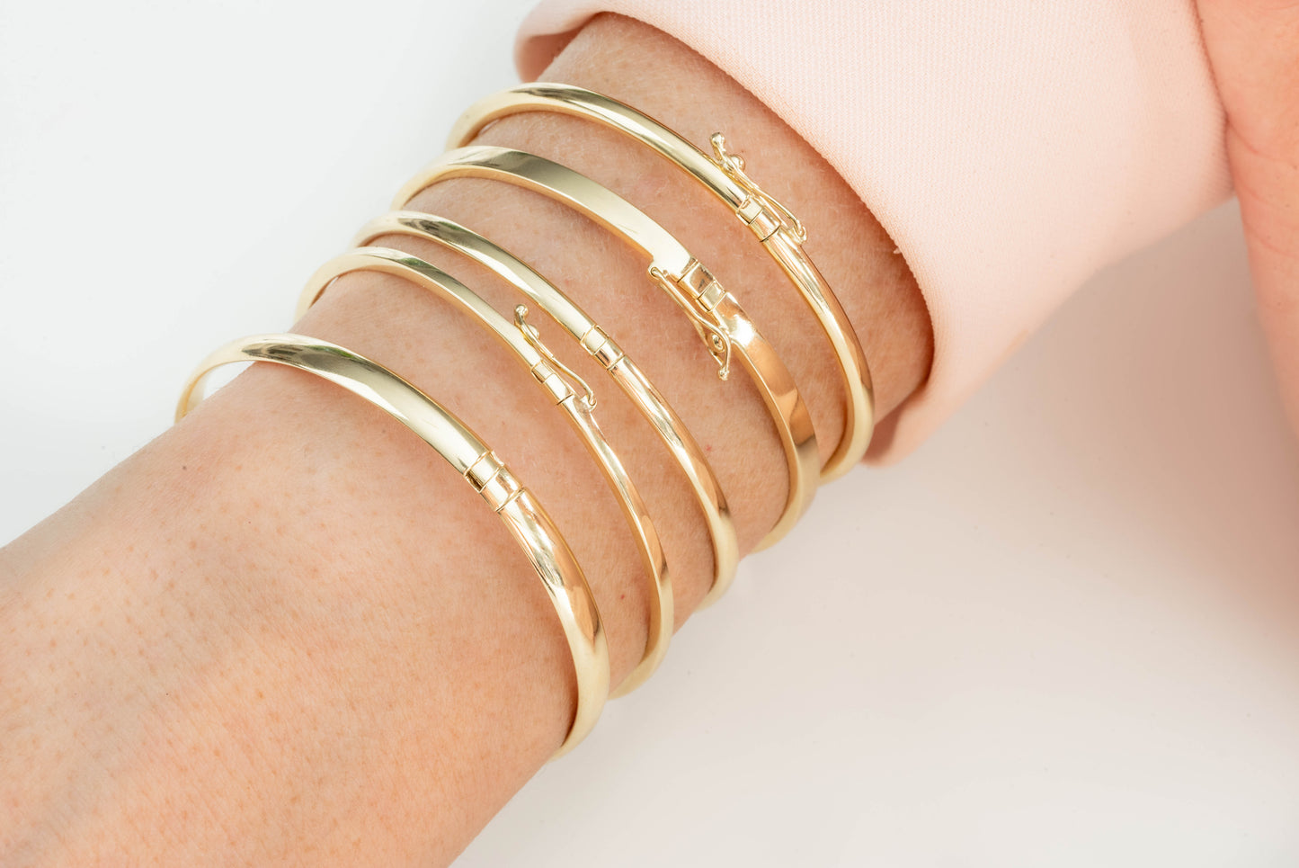 The picture captures a detailed view of a wrist embellished with multiple gold bangle bracelets.