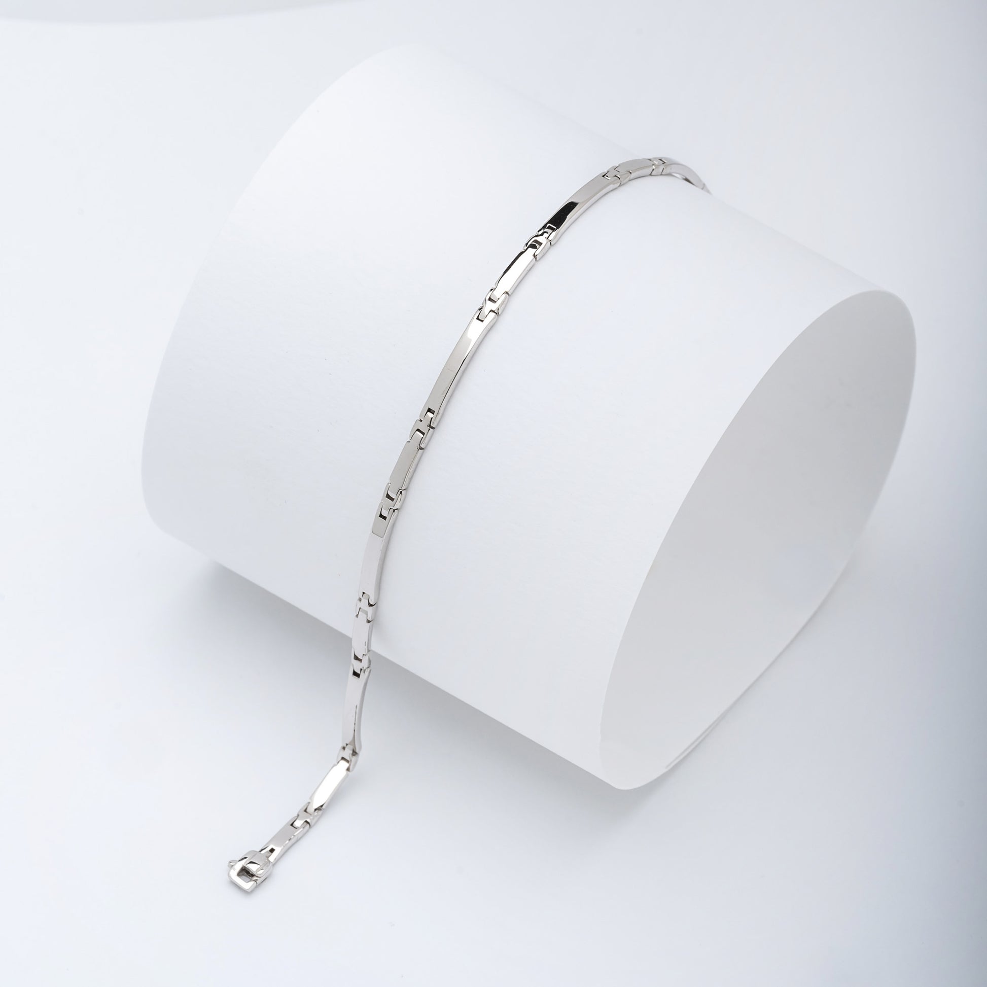 A sleek men's bracelet made of polished white gold. It features rectangular links connected by smaller rounded connectors, creating a clean, modern design with subtle detailing.