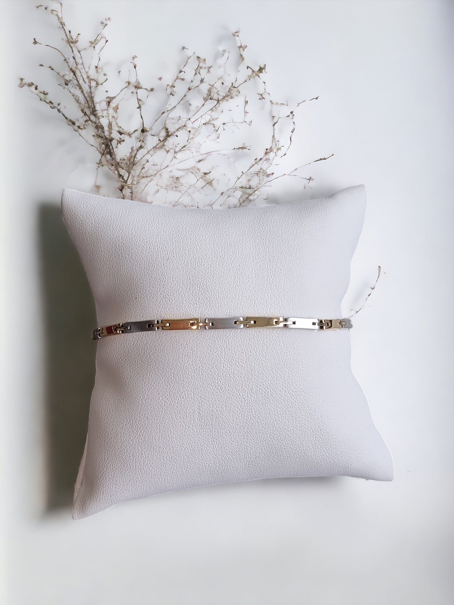 a sleek men's bracelet made of polished metal, yellow-white gold. It features rectangular links connected by smaller rounded connectors, creating a clean, modern design with subtle detailing.