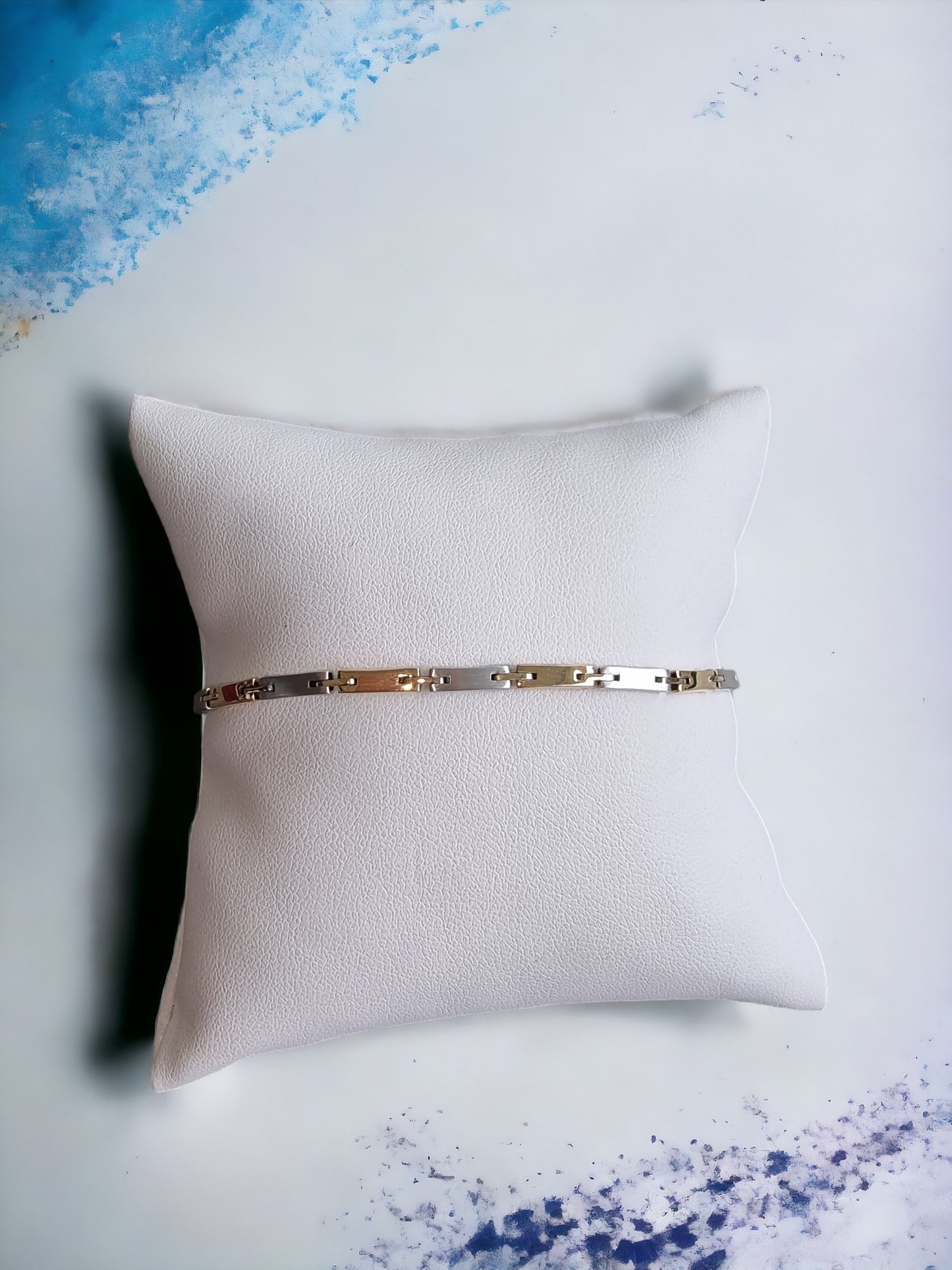 a sleek men's bracelet made of polished metal, yellow-white gold. It features rectangular links connected by smaller rounded connectors, creating a clean, modern design with subtle detailing.