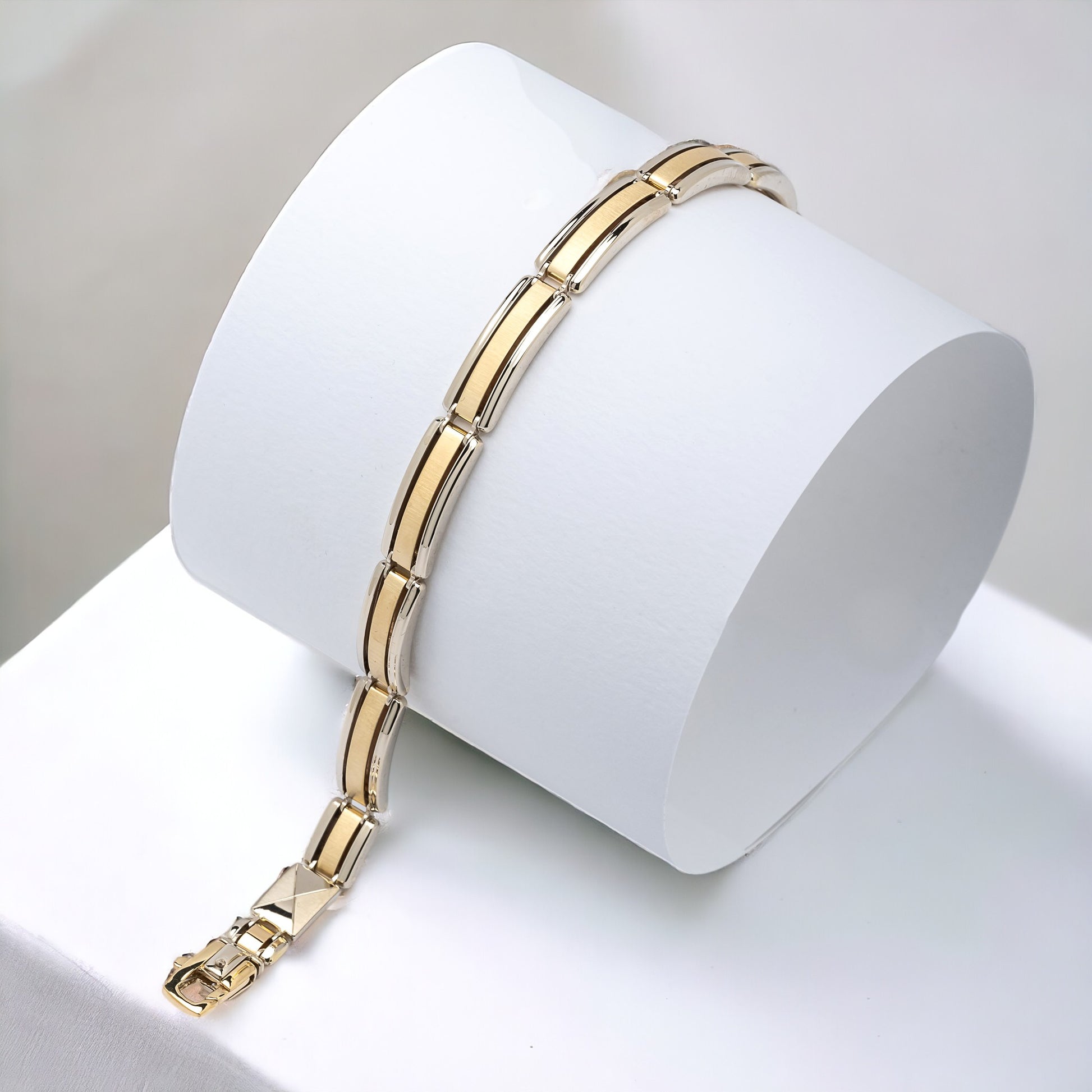 A men's bracelet crafted from yellow and white gold with a bold and structured look. It features wide, rectangular links that are slightly curved, creating a smooth, reflective surface.