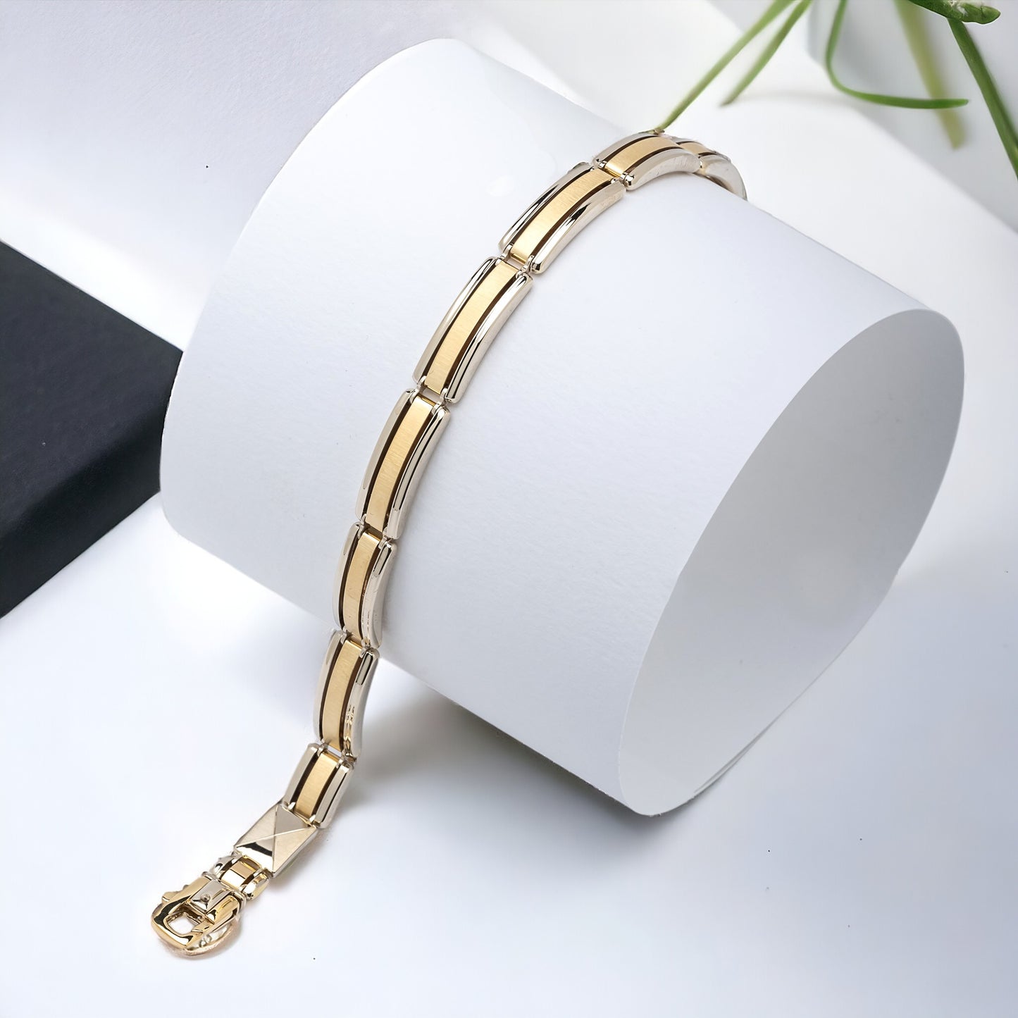 A men's bracelet crafted from yellow and white gold with a bold and structured look. It features wide, rectangular links that are slightly curved, creating a smooth, reflective surface.