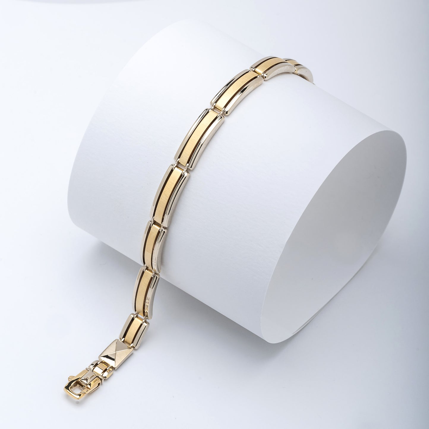 A men's bracelet crafted from yellow and white gold with a bold and structured look. It features wide, rectangular links that are slightly curved, creating a smooth, reflective surface.