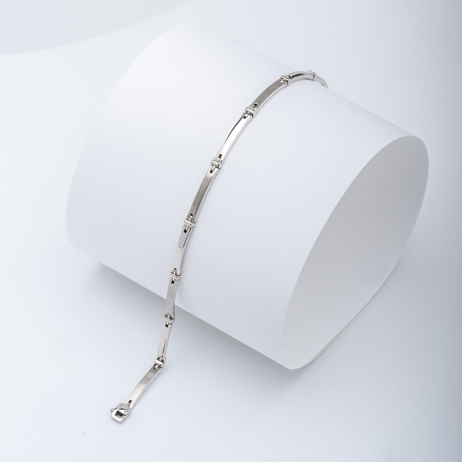 A sleek men's bracelet made of polished white gold. It features rectangular links connected by smaller rounded connectors, creating a clean, modern design with subtle detailing.