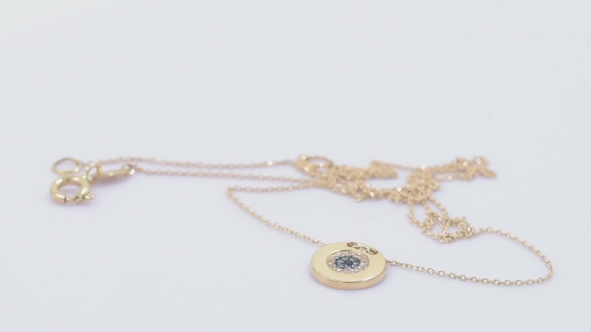 A women's round evil eye necklace, encrusted with cubic zirconia stones and crafted in 14k gold.