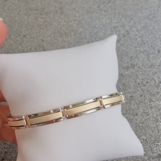 A men's bracelet crafted from yellow and white gold with a bold and structured look. It features wide, rectangular links that are slightly curved, creating a smooth, reflective surface.