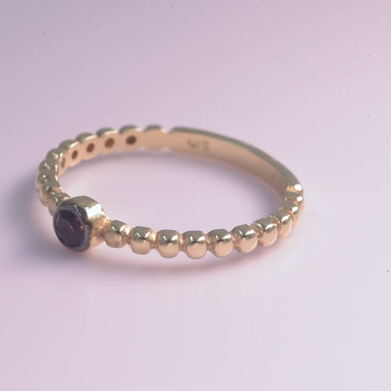 A beaded ring featuring a sapphire birthstone set in 14k gold.