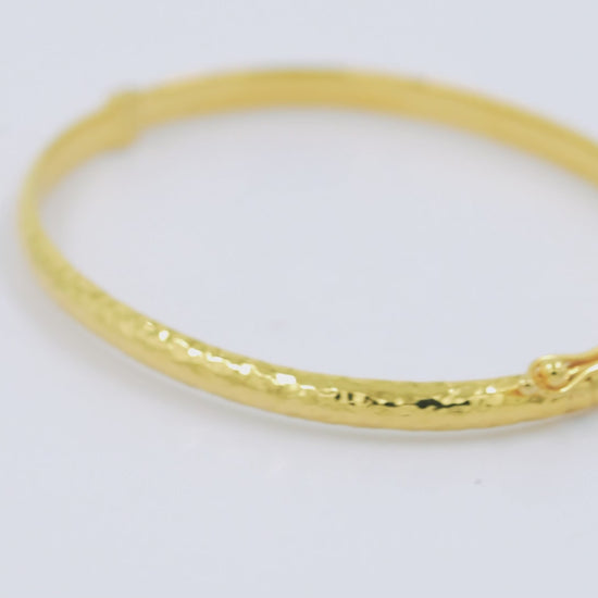 A 4.20mm hammered bangle bracelet in 14k gold, designed for women to adorn their wrist.