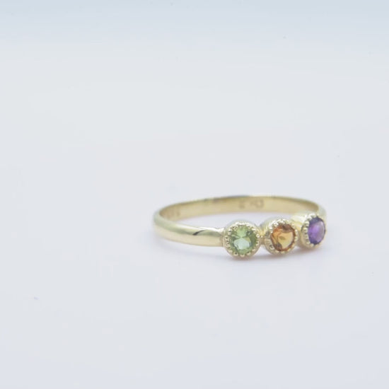 A handmade ring featuring three birthstones set in 14k solid gold with a prong setting.