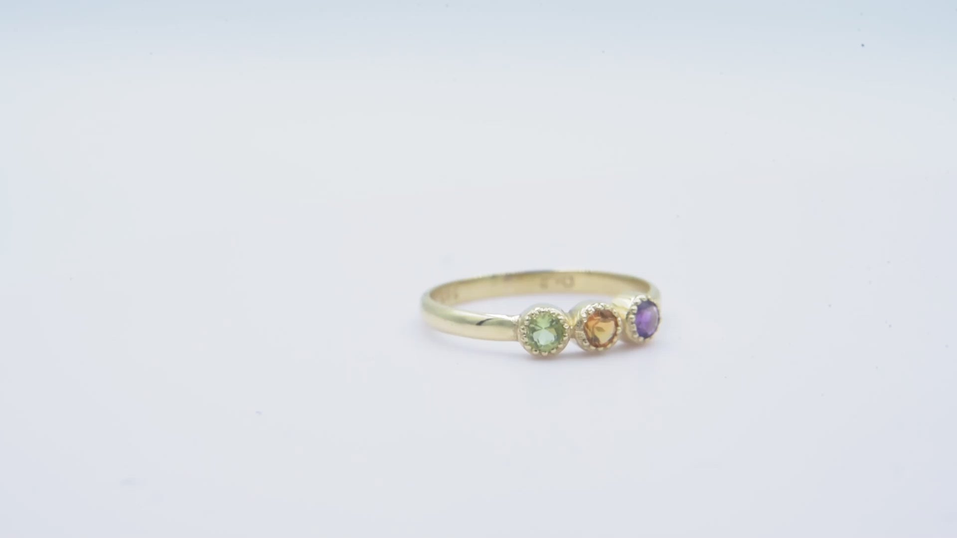 A handmade ring featuring three birthstones set in 14k solid gold with a prong setting.