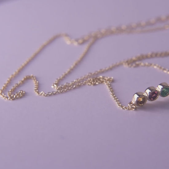 A 14k gold necklace for women, featuring five family birthstones.