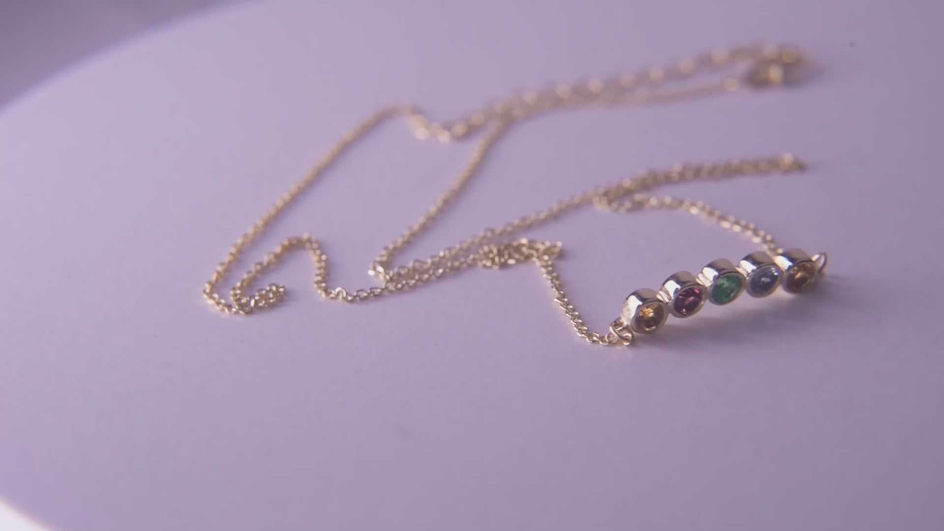 A 14k gold necklace for women, featuring five family birthstones.