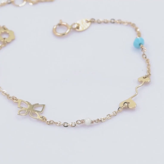 A 14k gold charm bracelet featuring an arrow, a flower, a butterfly, and three colorful gemstones.