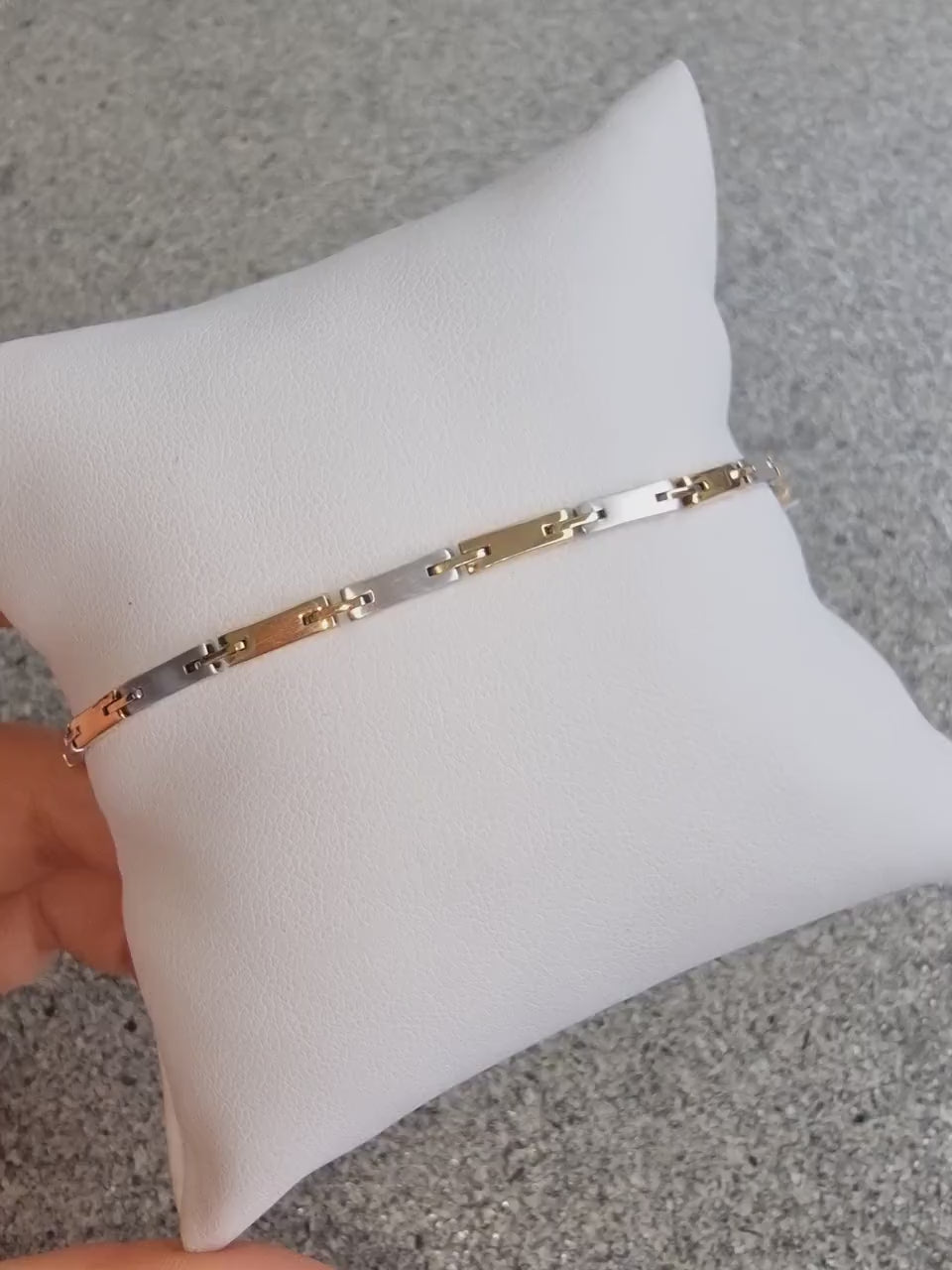 a sleek men's bracelet made of polished metal, yellow-white gold. It features rectangular links connected by smaller rounded connectors, creating a clean, modern design with subtle detailing.