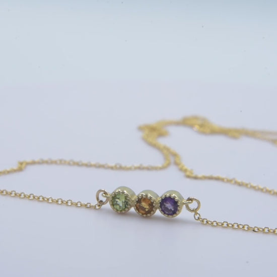 Handcrafted birthstone necklace in 14k gold, featuring three stones in a prong setting.