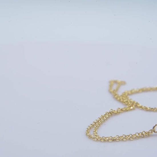 A handmade bracelet featuring a single birthstone set in 14k gold, complemented by a double chain design.