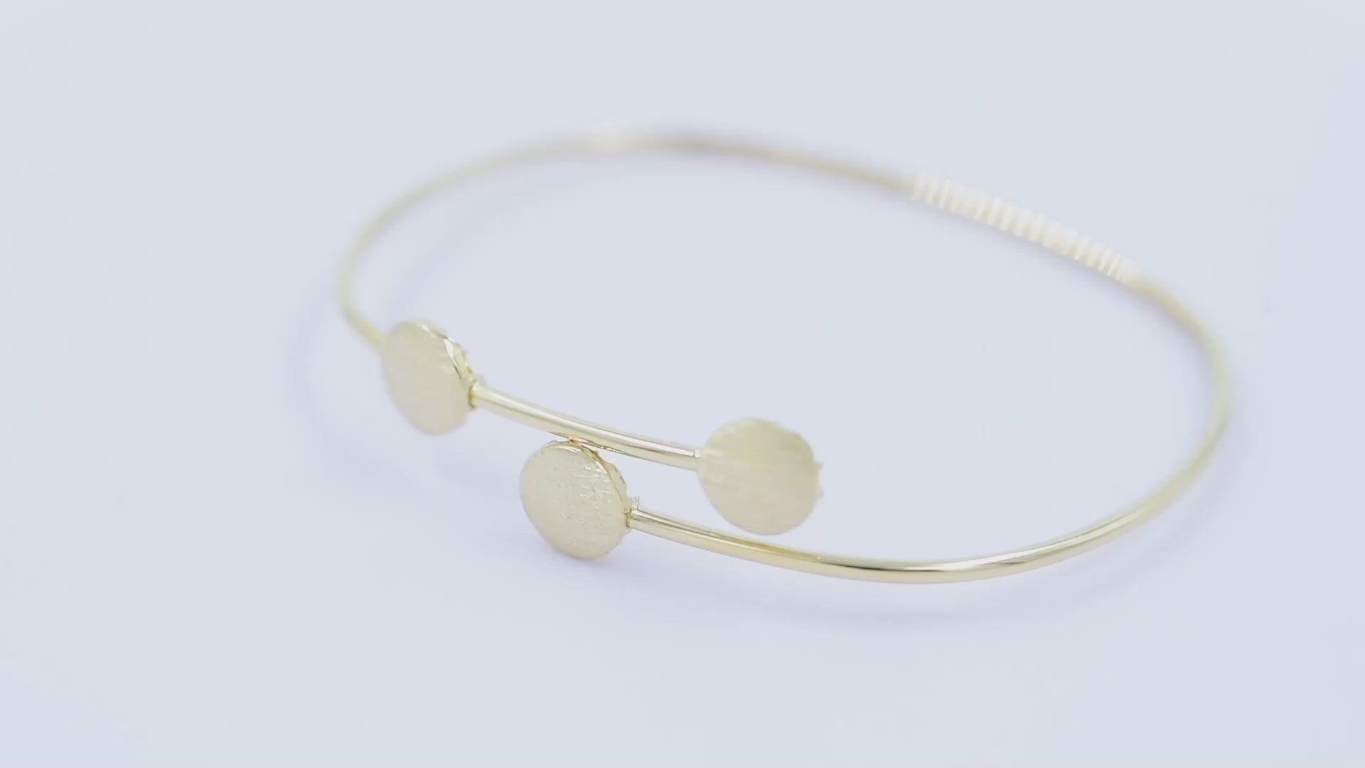 This photo features a minimalist gold open cuff bracelet with three textured round accents on the top.