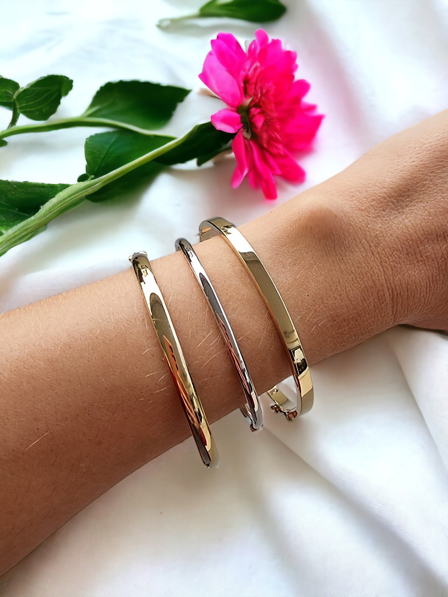 The image shows a close-up of a wrist adorned with several gold bangle bracelets