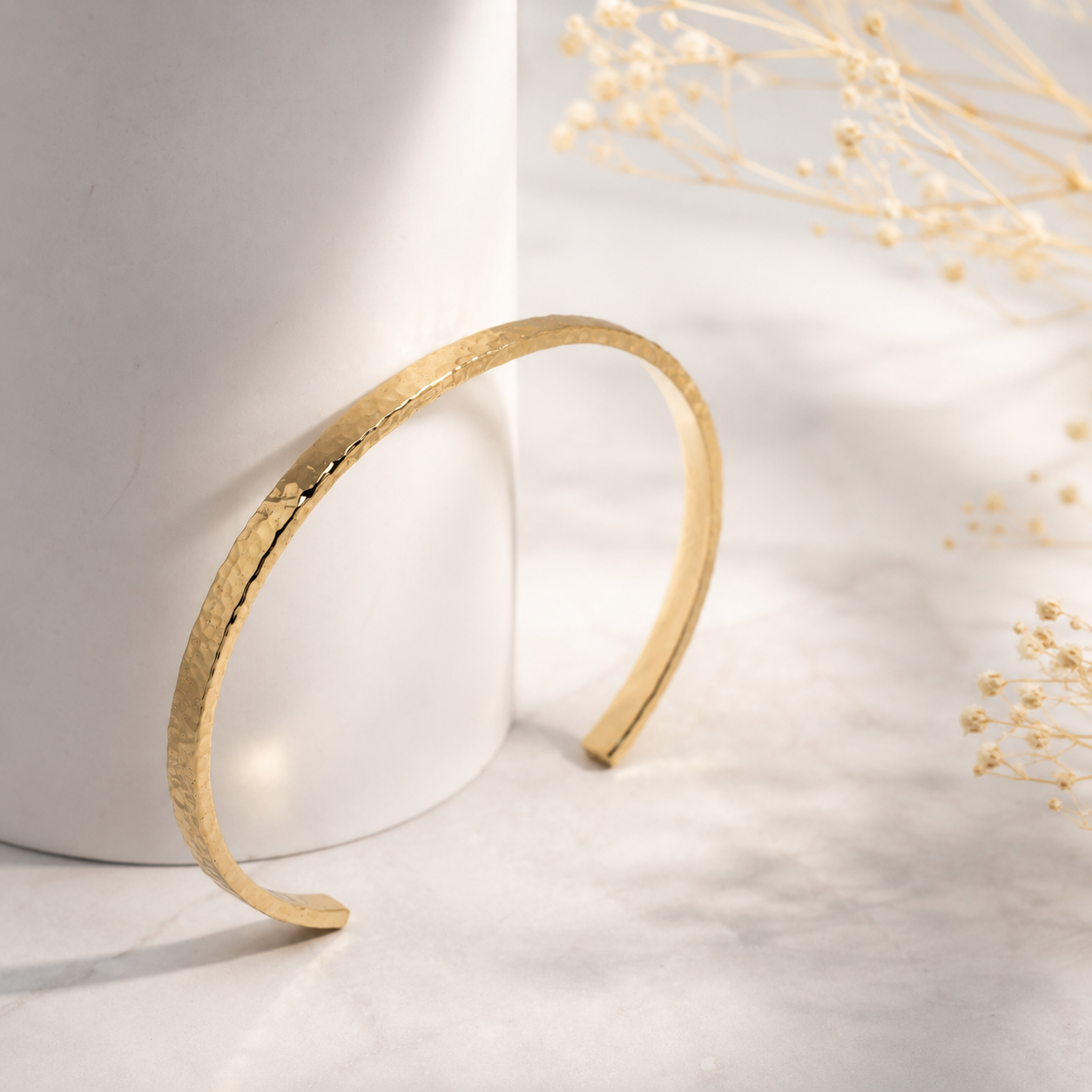 14k yellow Gold bangle bracelet on a white surface with a soft background