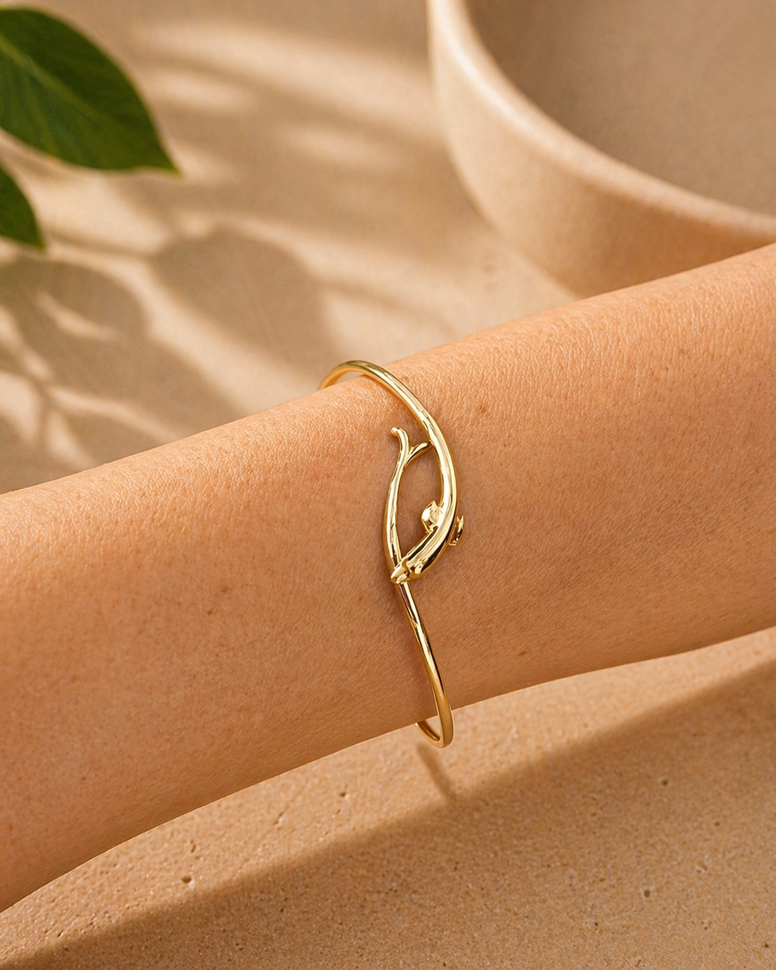 14k Gold dolphin bracelet on a wrist with a neutral background